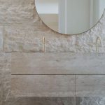 A wall with a mirror on it designed with Iran cream Travertine